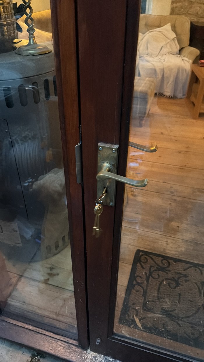 Old worn brass lever handle and lock on a glazed timber door